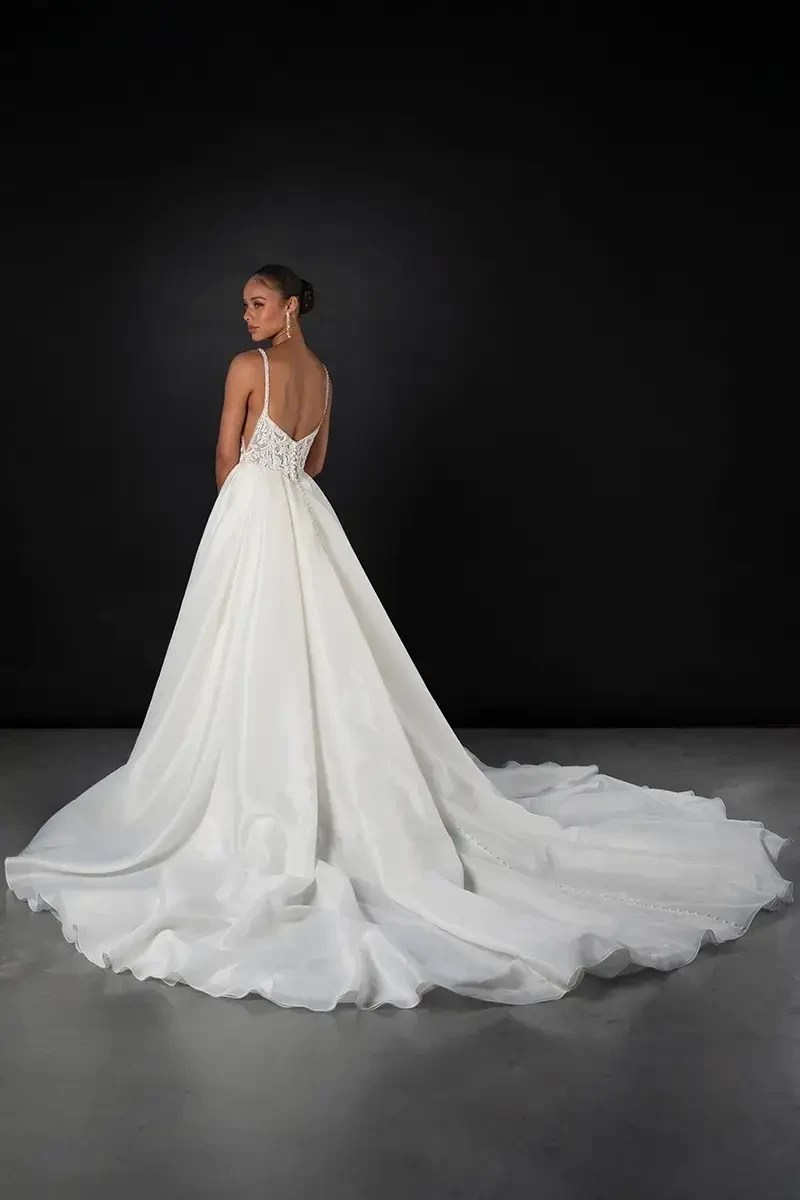 Model is wearing a square neckline wedding dress with a basque waist and pockets