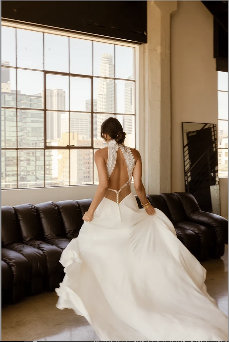 Model is wearing a halter wedding dress with a column silhouette