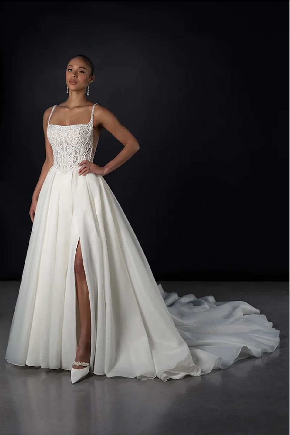 Model is wearing a square neckline wedding dress with a basque waist and pockets